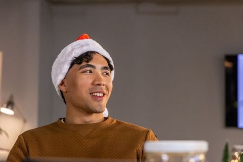 Asian man wearing santa hat smiling during cozy holiday office gathering