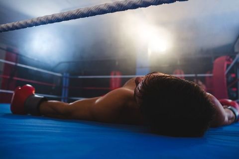 Boxer in glove collapse under hazy gym lights after match