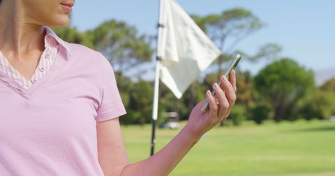 Female Golfer Using Mobile Phone on Sunny Golf Course
