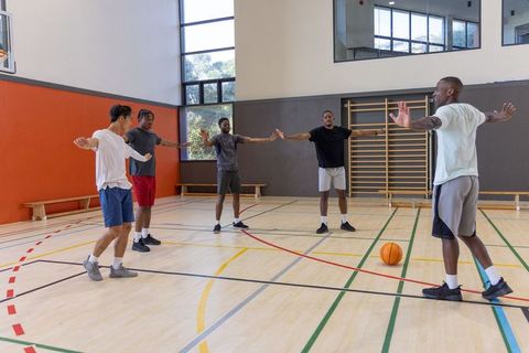 Basketball team practicing spacing and defensive drill in indoor gym with coach leading