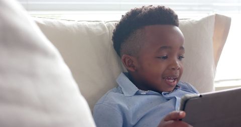 Young Boy Enthusiastically Using Tablet on Cozy Sofa - Download Free Stock Images Pikwizard.com