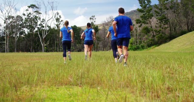 Group of Young Adults Jogging in Grassy Field for Fitness and Teamwork - Download Free Stock Images Pikwizard.com