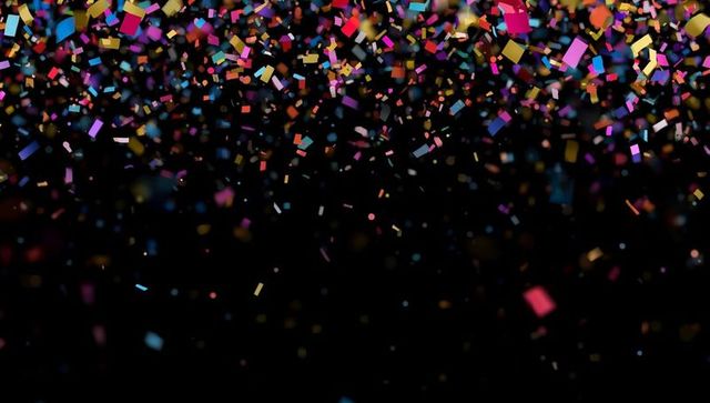 Vibrant multicolored confetti falling on black background