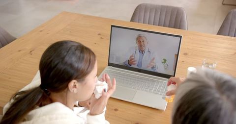 Woman in Online Consultation with Doctor Via Laptop and Holding Medicines
