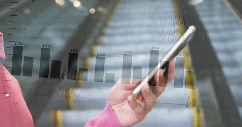 Holding smartphone with translucent financial charts overlay over escalator commute