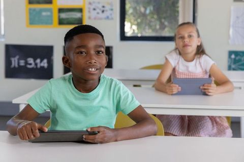 Primary students sitting with tablets in classroom learning math and digital literacy