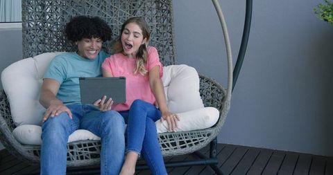 Young Couple Engaging with Tablet on Modern Patio Swing