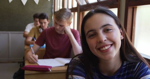 Smiling Teenage Girl in Classroom with Classmates Studying - Download Free Stock Images Pikwizard.com