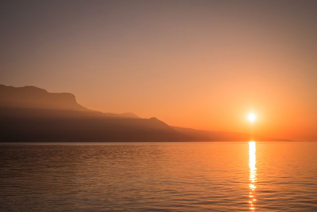 Serene Sunset Over Calm Lake with Mountain Silhouette - Download Free Stock Photos Pikwizard.com