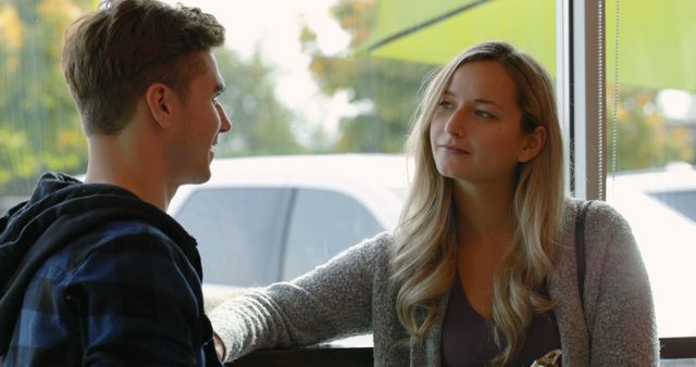 Young couple interacting with each other in cafe. Couple standing near window in cafe 4k