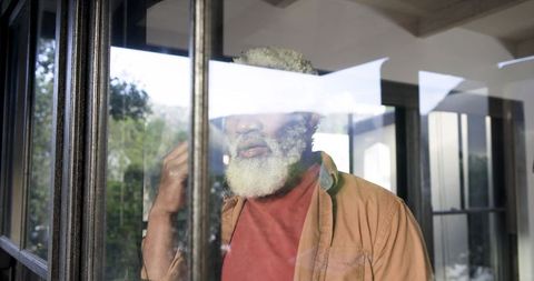 Senior Man Relaxing at Home Behind Reflective Glass
