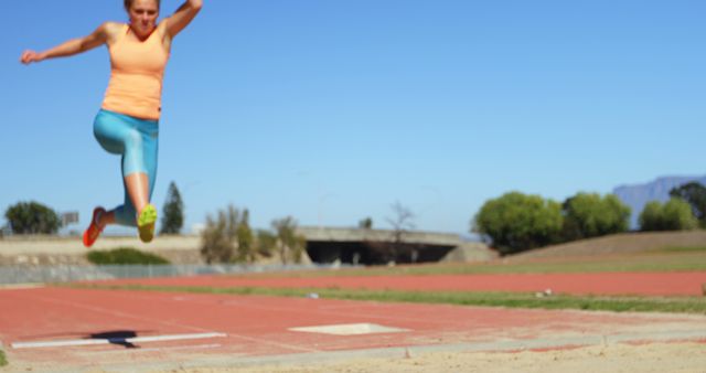 Female Athlete Long Jumping on Track Field in Daytime - Download Free Stock Images Pikwizard.com