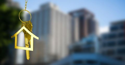 Golden Key with House Symbol Hanging Over Urban Skyline