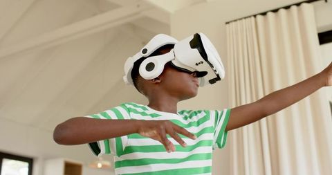 African American Boy Wearing White VR Headset Reaching and Interacting in Living Room