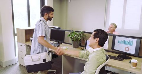 Professional coworkers shaking hands in modern open office