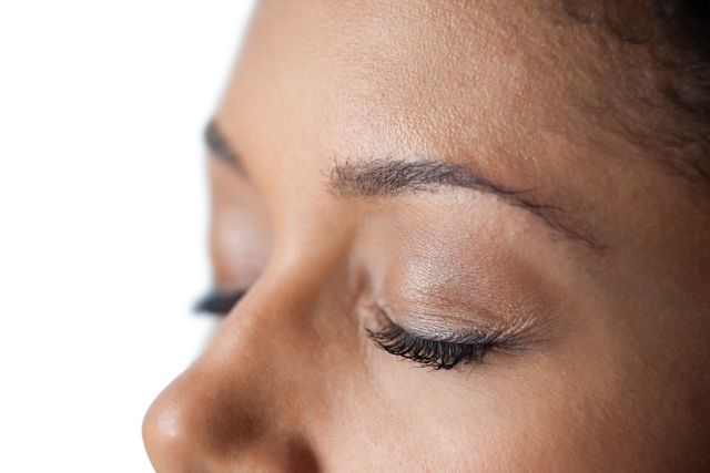 Close-up of closed womans eye and nose against white background