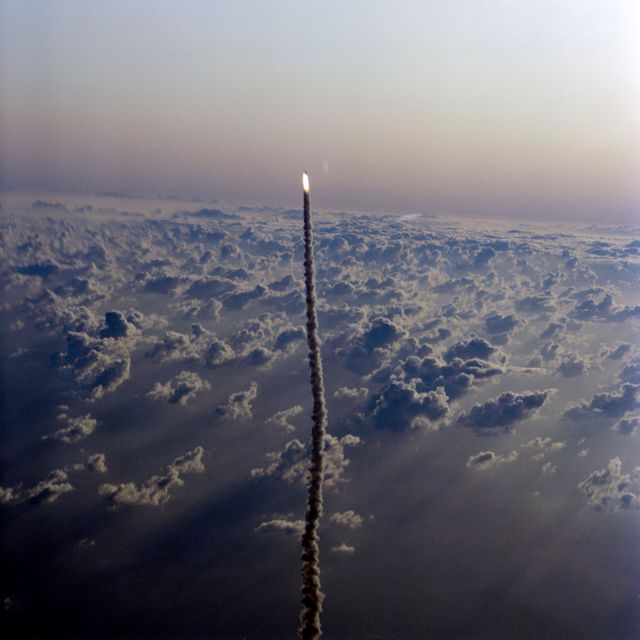 Aerial view of Space Shuttle Columbia ascending through clouds during STS-5 launch on November 11, 1982. This historic event is prominent in space exploration. Ideal for educational materials on space history, documentaries, and articles on space missions and NASA achievements.
