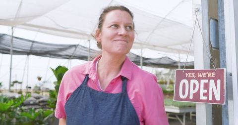Smiling Senior Woman Welcoming Guests at Nursery Entrance
