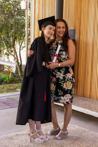 Proud Mother with Graduate in Cap and Gown Embracing on Outdoor Patio