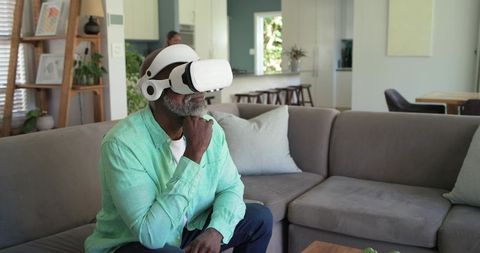 Senior African American Man Exploring Virtual Reality at Home on Modern Gray Sofa