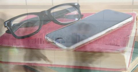 Glasses and smartphone resting on hardcover book with window reflection and daylight