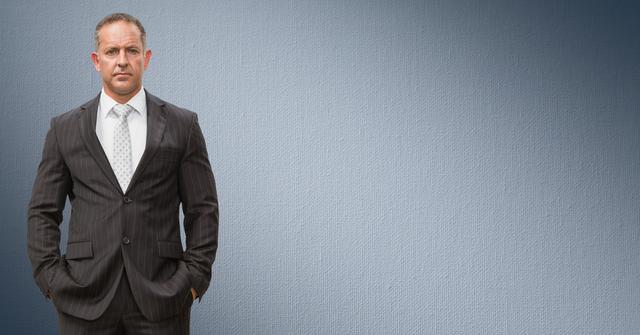 Confident Businessman Standing with Hands in Pockets Against Grey Background - Download Free Stock Photos Pikwizard.com