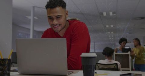 Professional in Red Sweater Engaging with Laptop in Modern Office