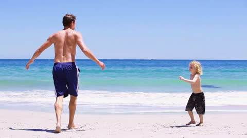 Father Playing Joyfully with Son on Sunny Beach