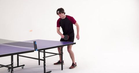 Male Athlete in Studio Playing Table Tennis Energetically with Paddle
