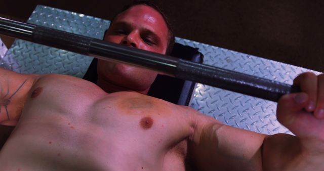 Muscular man performing a bench press exercise on a steel platform in a gym. This image can be used for promoting workout programs, fitness centers, strength training guides, and bodybuilding campaigns.