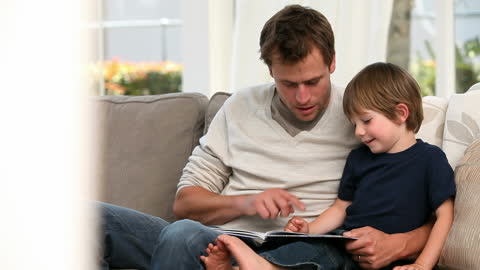 Father Reading Storybook with Young Son on Sofa