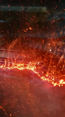 Vertical molten metal band pulsing and sending embers over rippled fiery surface closeup