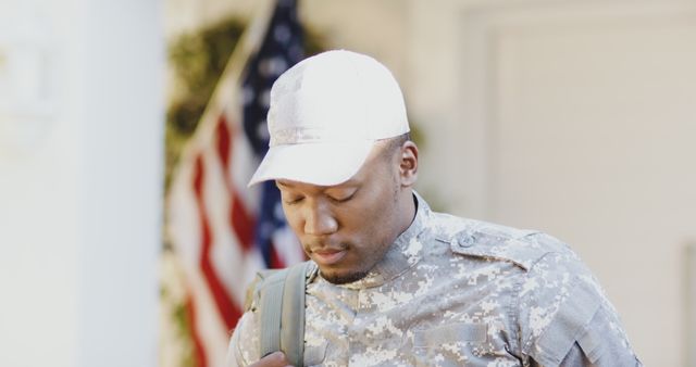 Soldier is standing wearing a camouflage uniform and a cap with an American flag in the background. This image can be used to represent themes such as military service, patriotism, discipline, and dedication. It is suitable for military recruitment campaigns, patriotic events, and promotions emphasizing sacrifice and service.