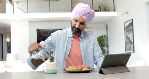 Man in Turban Using Tablet During Relaxed Morning Breakfast