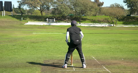 Cricketer in Action on Sunny Field Preparing to Bat