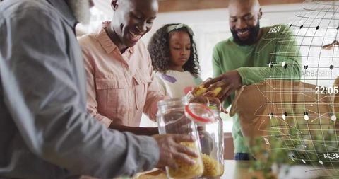 Multigenerational family organizing pantry: smiling adults pouring pasta into glass jars