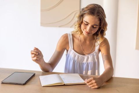 Young woman journaling at minimal desk, calm focused lifestyle, planning and mindfulness
