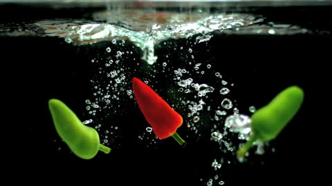 Chili Peppers Falling into Water with Splash and Bubbles