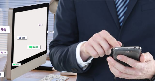 Business professional interacts with smartphone while computer screen displays analytics in office setting. Ideal for depicting business communication, modern technology usage, social media engagement, and data analysis in corporate environments.