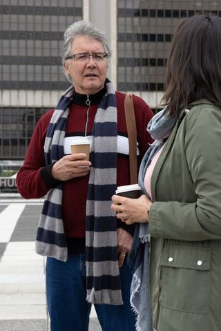 Senior man and woman chatting over takeaway coffee in urban office plaza