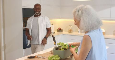 Senior couple planting herbs in modern kitchen