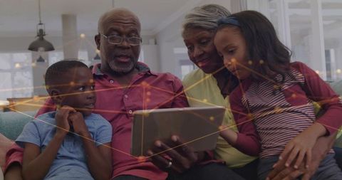 Multigenerational family sharing tablet on sofa showing digital connection and togetherness