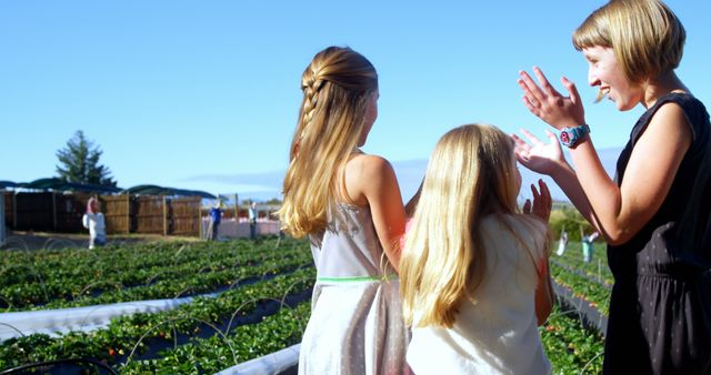 Mother and daughters enjoying outdoor strawberry farm. Ideal for concepts related to family outings, agriculture tourism, healthy lifestyles, summer activities, and organic farming promotions.