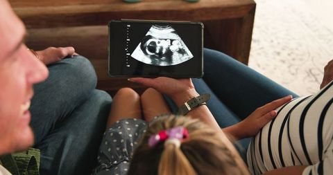 Family watching ultrasound scan together on tablet