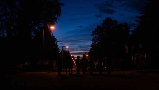 Children tricking-or-treating at dusk under warm street lamps