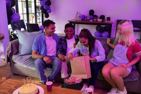 Friends Celebrating Birthday Checking Gifts Joyfully in Living Room