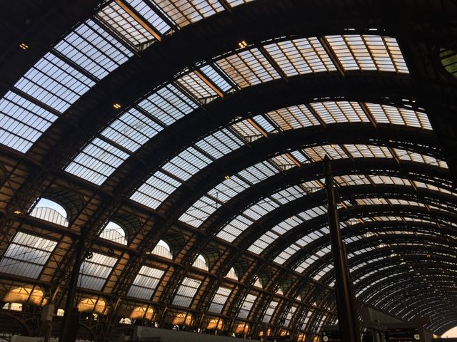 This photo shows a modern train station featuring an arched metal roof structure with large windows. It is ideal for articles or campaigns about urban transit, architectural designs, transportation hubs, or modern infrastructure. The image can be used in blogs, presentations, or travel magazines to highlight the dynamic structure of contemporary railway stations.