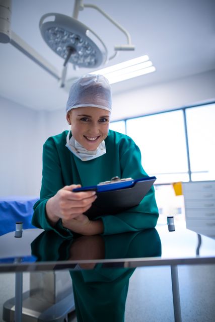 This image depicts a smiling female surgeon holding a clipboard in an operating room. The bright and clean environment suggests a modern medical facility. This image can be used for healthcare-related content, medical websites, hospital brochures, and educational materials about surgery and healthcare professions.
