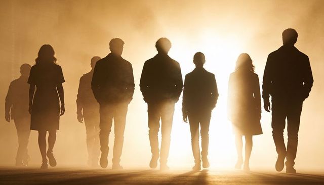 Silhouetted group walking toward camera in dramatic golden backlight, unity and mystery