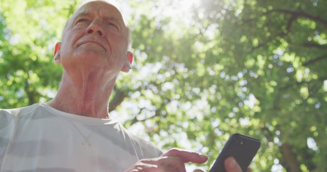 Senior Man Using Smartphone and Earphones in Park - Download Free Stock Images Pikwizard.com